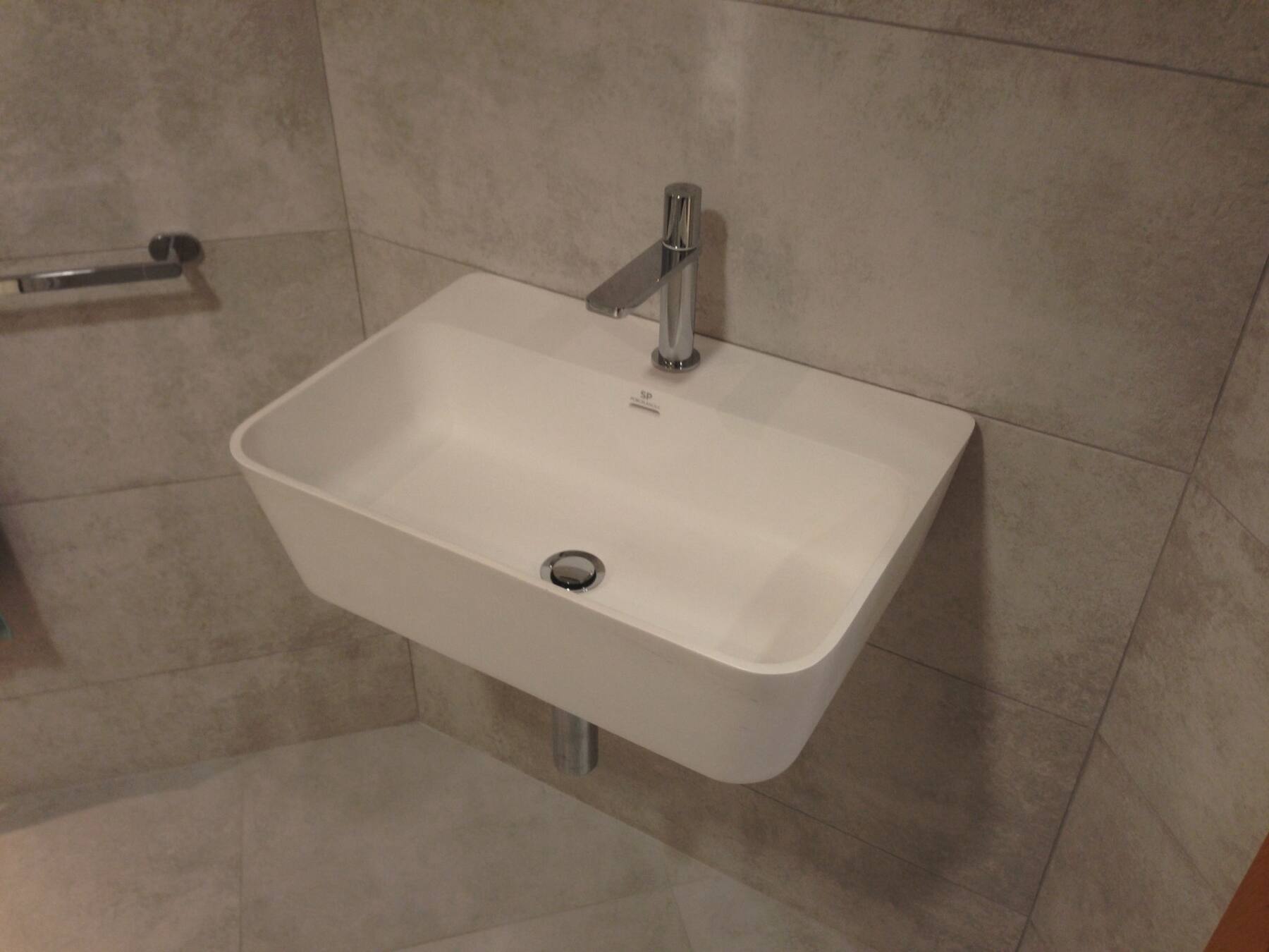 Wall-hung basin against large grey wall tiles