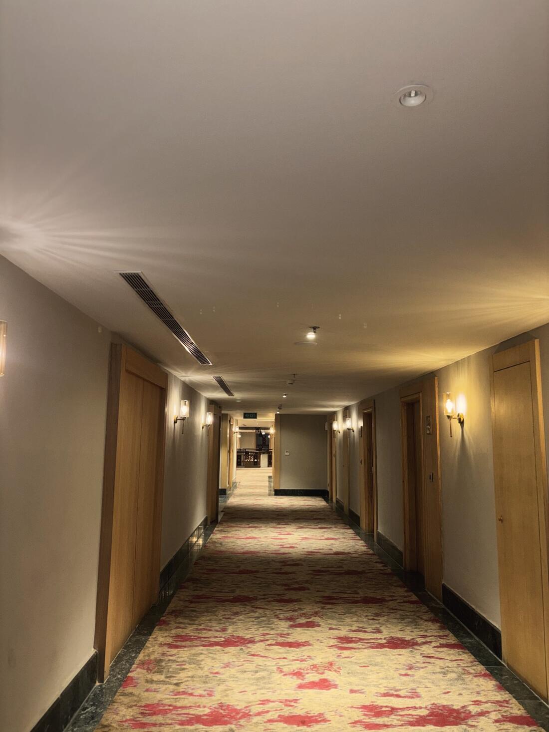 Long hotel corridor with wall lights and patterned carpet