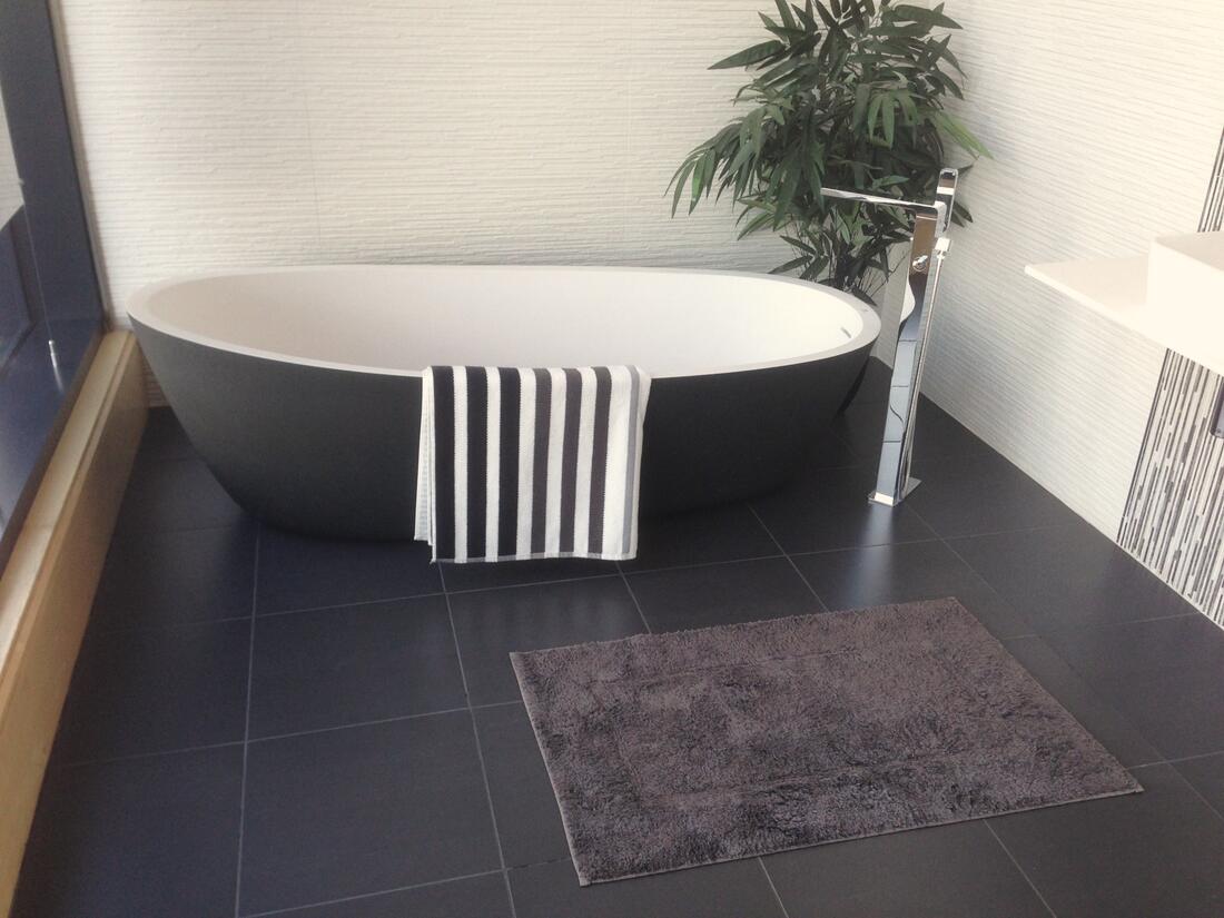 Freestanding bath on dark floor tiles in a renovated bathroom